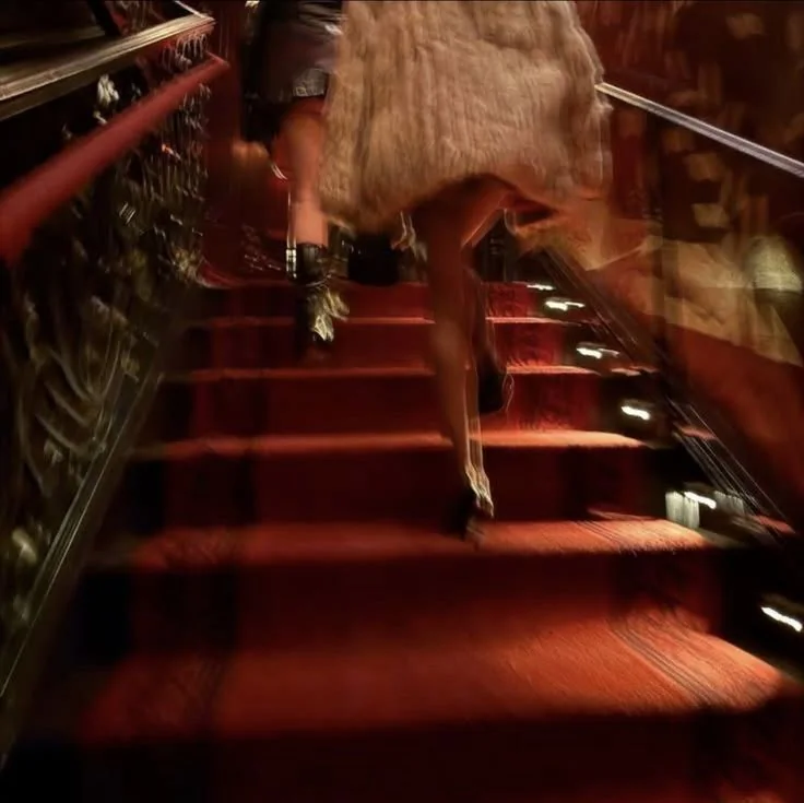 Blurred figure climbing a red-carpeted staircase